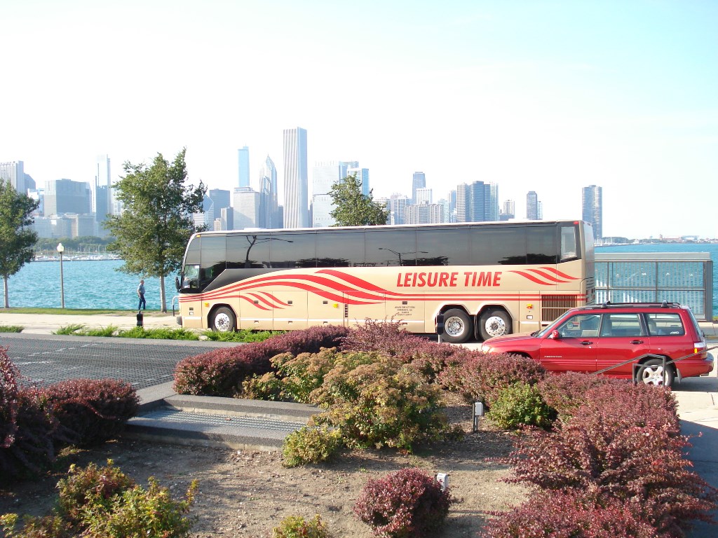 Bus parked by river in front of city skyline